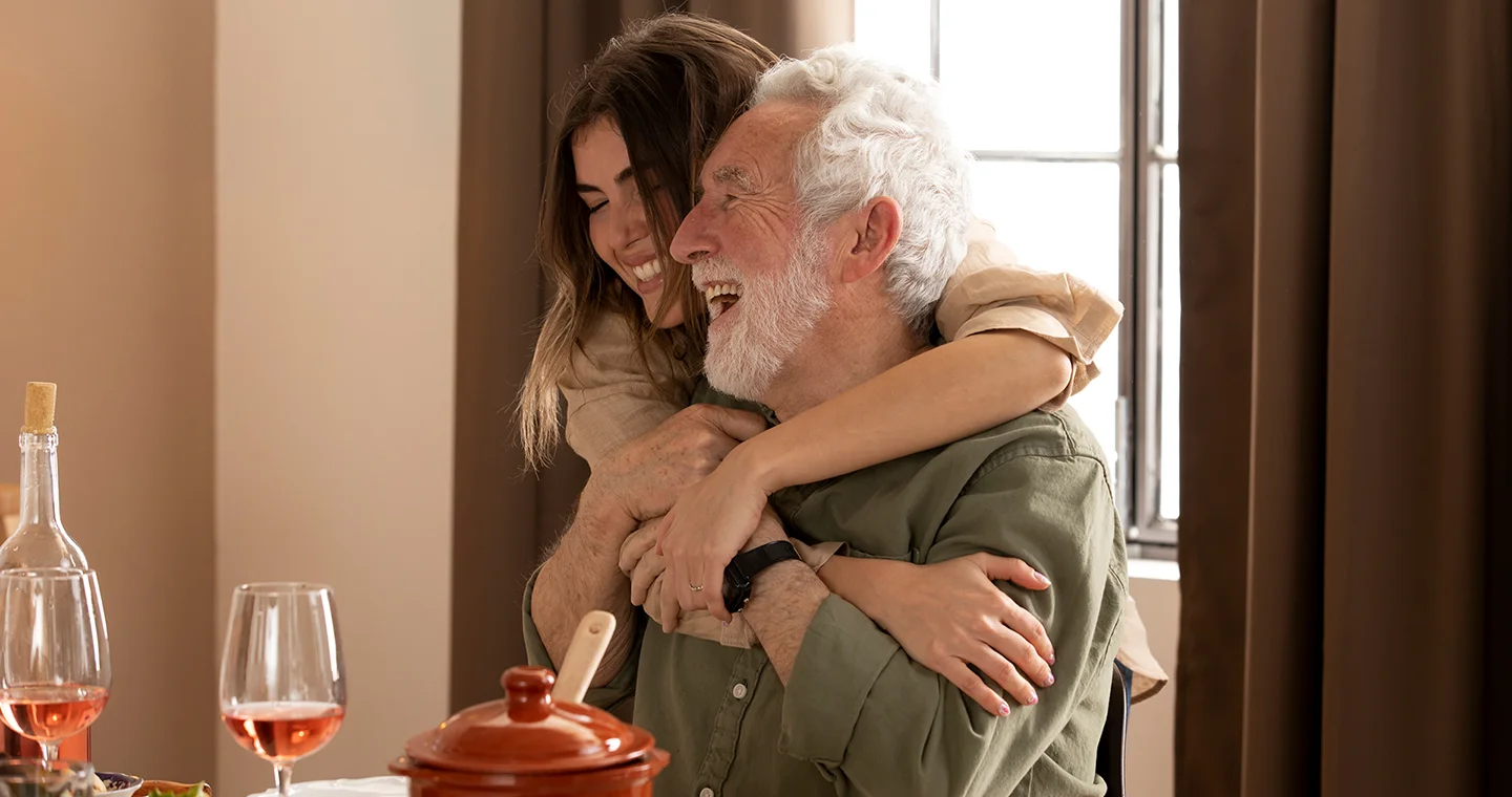 Smiling elderly man hugging young woman